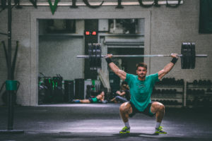 Male athlete snatching alone in a large gym.