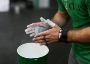 Athlete chalking their hands over the chalk bucket.