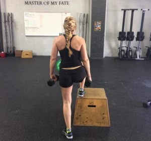 Female athlete doing weighted box step-ups.