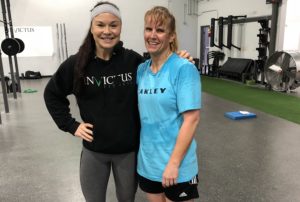 A female athlete and her coach pose while smiling.