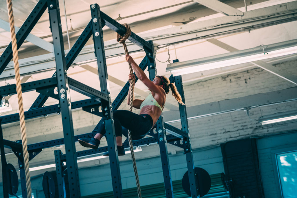 female athlete at the top of a rope climb