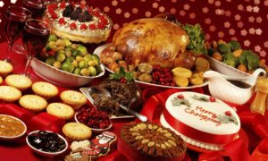 Full spread of food on a table decorated for Christmas.