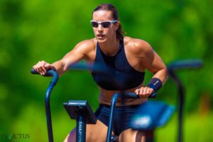 Female athlete wearing sunglasses while riding the Assault Bike outside.