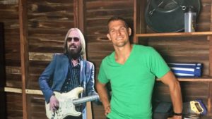 Man posing in front of life-size cut-out of Tom Petty playing the electric guitar.