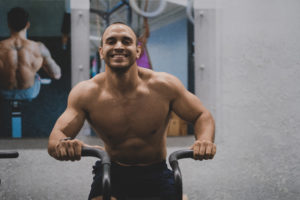 Smiling shirtless male athlete riding the Assault Bike.