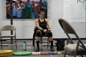 Lifter at a weightlifting meet considers her strategy for adding weight to the bar.