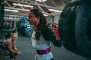 Female athlete wearing a lifting belt and going for a personal record back squat.