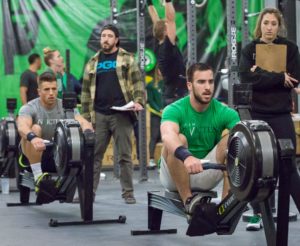 Two Invictus athletes rowing during The CrossFit Open while their judges watch them closely.