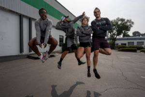 Members of the Invictus weightlifting team do a unison jumping pose outside the gym.