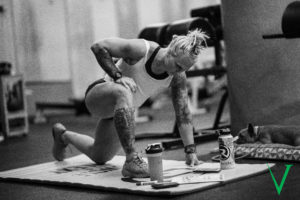 Female athlete stretching while looking at her workout program.
