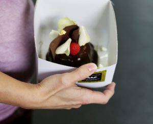 Hand holding a delicious chocolate desert in a fancy desert box.