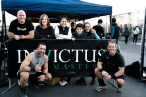 Group of athletes posing around the Invictus tent at a local competition.