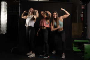 Three female athletes doing silly versions of body building poses and laughing.