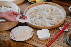 Person making Asian dumplings by hand.
