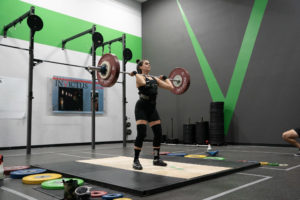 Female weightlifter on the platform in a singlet just before she nails her PR jerk in competition.