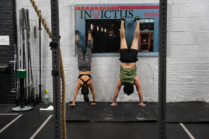 A male and a female athlete performing nose-to-wall handstands.