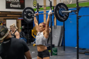 Invictus Masters Athlete, MA, holding a barbell overhead.