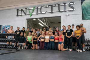 Large group of athletes posing under the Invictus sign after class.