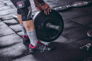 Man loading barbell who is smart and wearing weightlifting shoes.