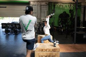 Coach Holden watching an Invictus Athlete snatch in personalized programming